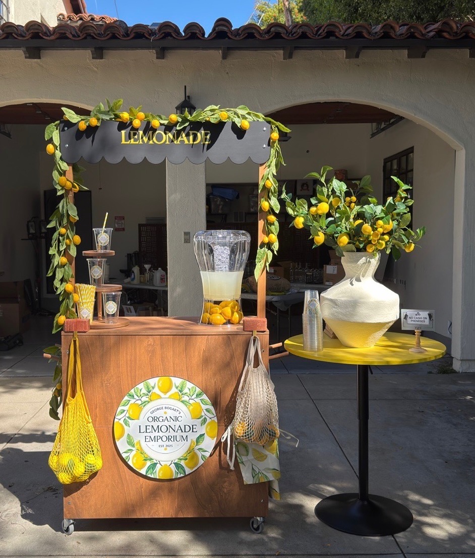 The lemonade stand set dressed with artificial lemons and garlands, standing outside a Spanish-style house